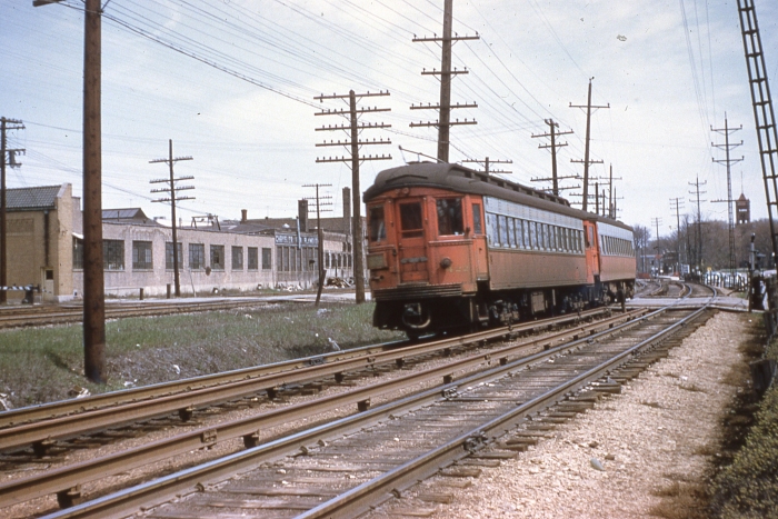 #2 - Two car Chicago Aurora & Elgin train headed by Cincinnati steel 422 with a postwar St. Louis steel westbound on CA&E tracks in Wheaton. The approximate location, as determined through Googole Maps, is about 188 S. Wheaton Ave., the current location of the Illinois Prairie Path. (Mr. Foelschow thought this was Forest Park, but the buildings in the picture match up with Wheaton. The other tracks at left are the C&NW (present-day Union Pacific West Line). Answer: CA&E 457-422 at Wheaton on April 21, 1957. (Photo by Ray DeGroote)