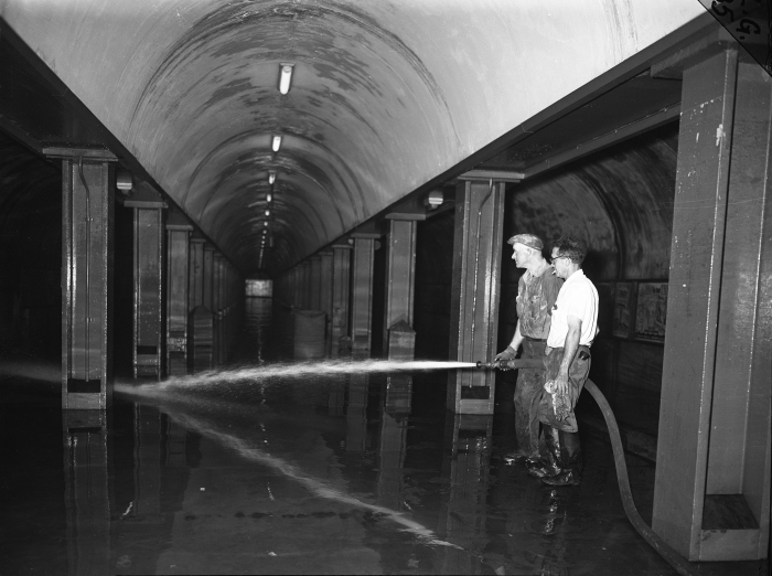 Workmen William Metzger and Dennis Moriarty wash down the muck left by the flood on the platform of the subway at Congress and LaSalle streets on July 14, 1957. (Editor's collection)