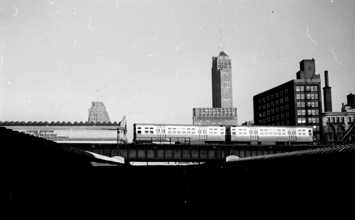 Frame 9 - "6000-series train, presumably Douglas, on Met "L" mainline east of Canal. over Union Station trainshed, viewed from Van Buren Street in front of the Main Post Office." -GF